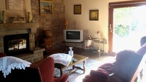 Una sala de estar acogedora con chimenea de piedra, televisor y asientos cómodos.