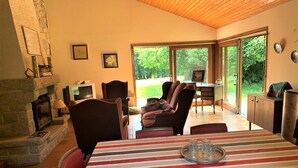 Un comedor con mantel a rayas, sillas, chimenea y vistas al exterior.