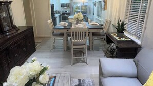 A modern living room with a sofa, a coffee table, and a dining area with a table and chairs.