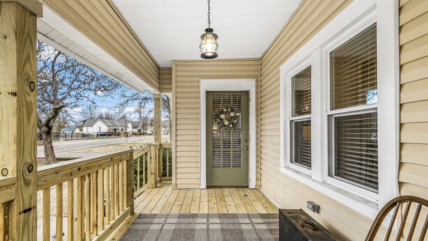 A porch with a wooden railing, a bench, and a door with a wreath.