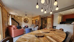 A modern living room with a large wooden dining table, leather sofas, and a fireplace. - 100% RENOVATED FAMILY CHALET with view! (Arvieux)