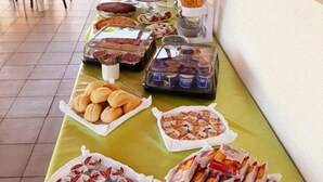 Une table de buffet proposant divers plats, notamment des pâtisseries, des sandwichs et des boissons.