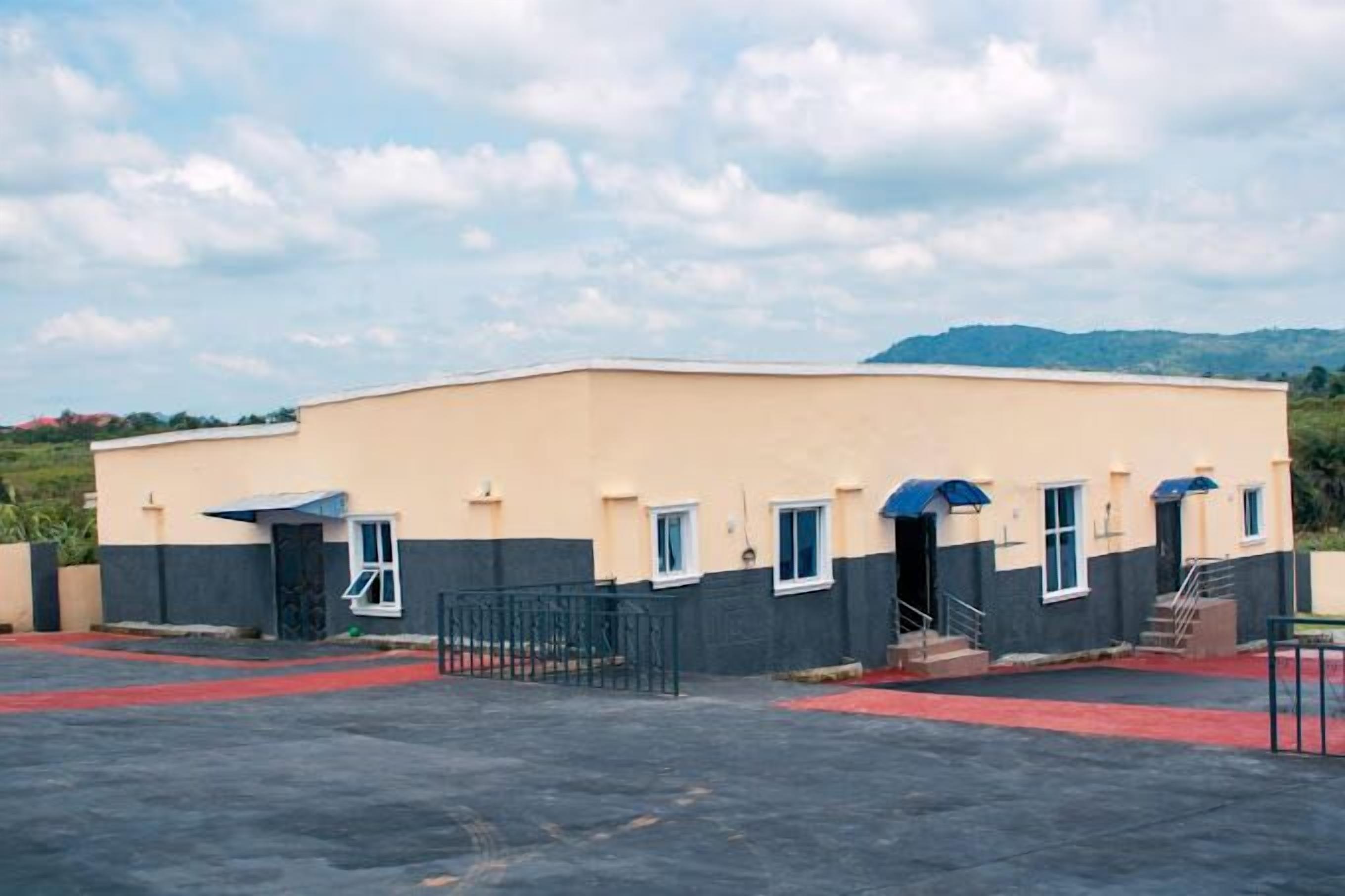 A two-story building with a flat roof, a gated entrance, and a red carpet leading to the entrance.