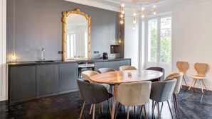 Een moderne keuken met een groot eiland, donkere kasten en een ronde houten eettafel met stoelen.