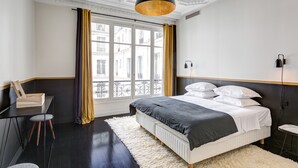 Een moderne slaapkamer met een groot bed, een bureau en een raam met gordijnen.