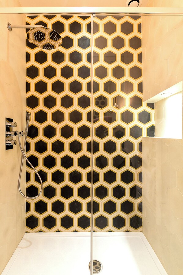 A shower with a geometric tile pattern and a handheld showerhead. - Le Opera Drouot (Paris)