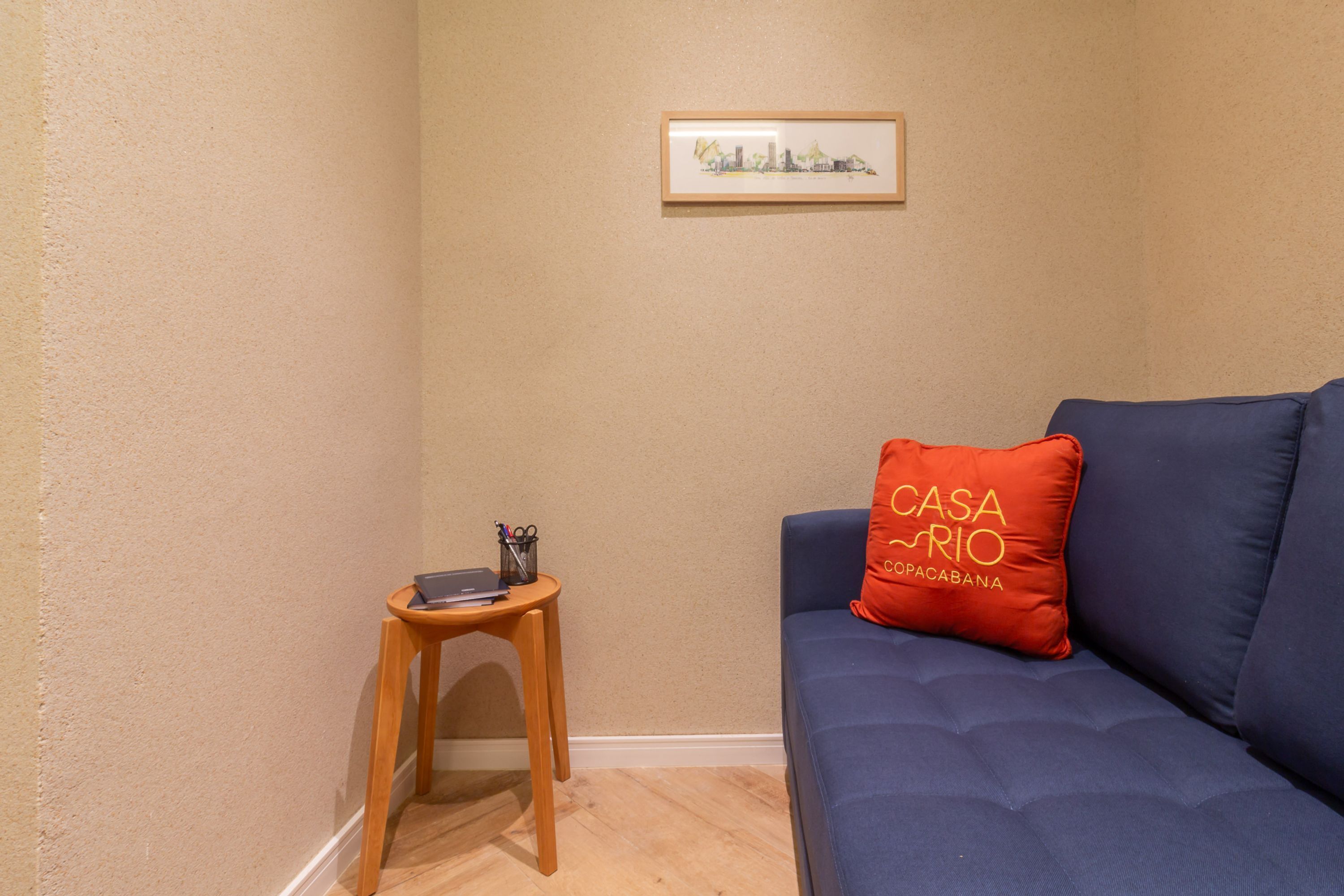 A room with a blue sofa, a small wooden side table, and a framed picture on the wall.