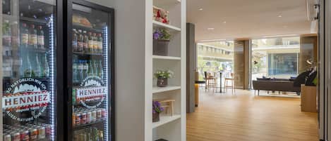 A modern interior with two beverage dispensers, wooden flooring, and a seating area with a sofa and chairs.