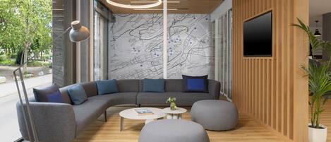 Un interior moderno con un sofá modular, otomanos redondos, una mesa de centro y un televisor montado en una pared de madera.