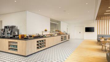 Una cocina moderna con una isla central, electrodomésticos integrados y una zona de estar con mesas y sillas.