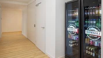A hallway with a refrigerator stocked with beverages and a door at the end.