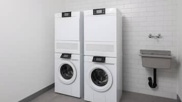 A laundry room with two stacked front-loading washing machines and a sink.