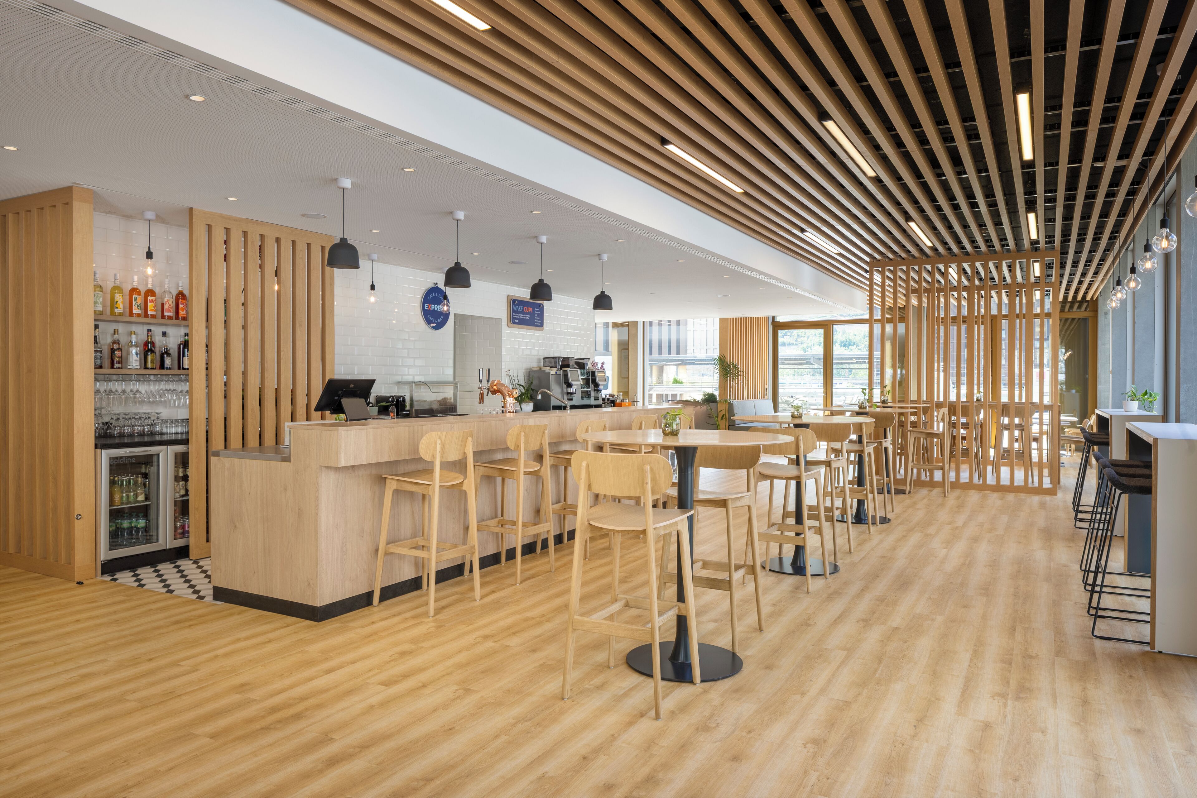 Ein modernes Café-Interieur mit Holztischen, einer Bar und einer Sitzgelegenheit.