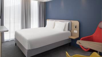 Una habitación de hotel con cama, escritorio y silla.