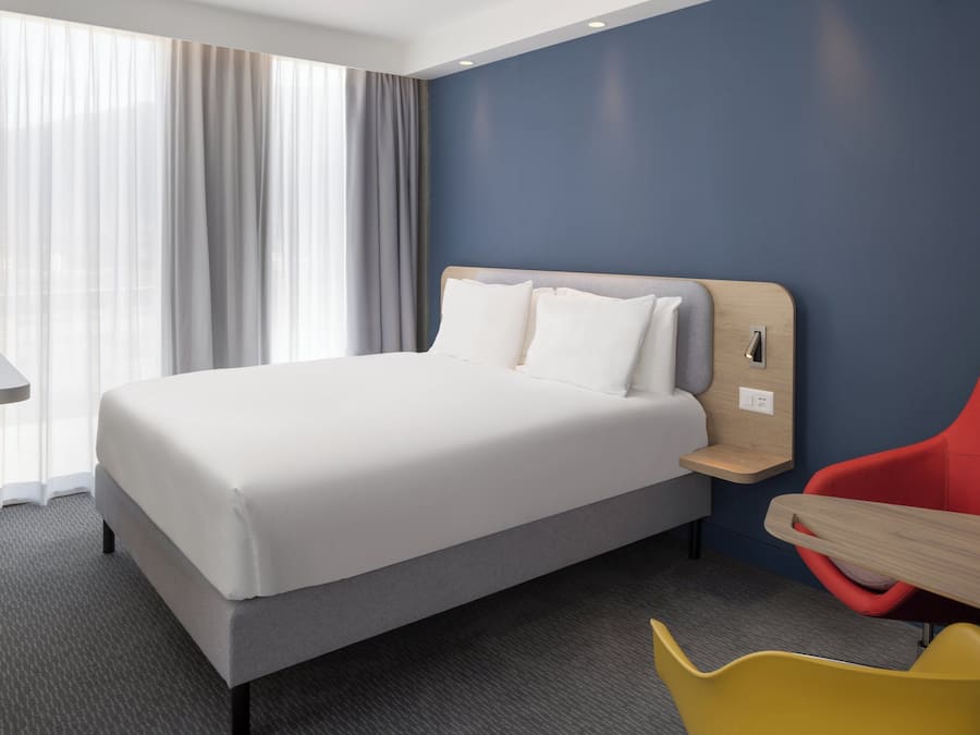 Una habitación de hotel con cama, escritorio y silla.