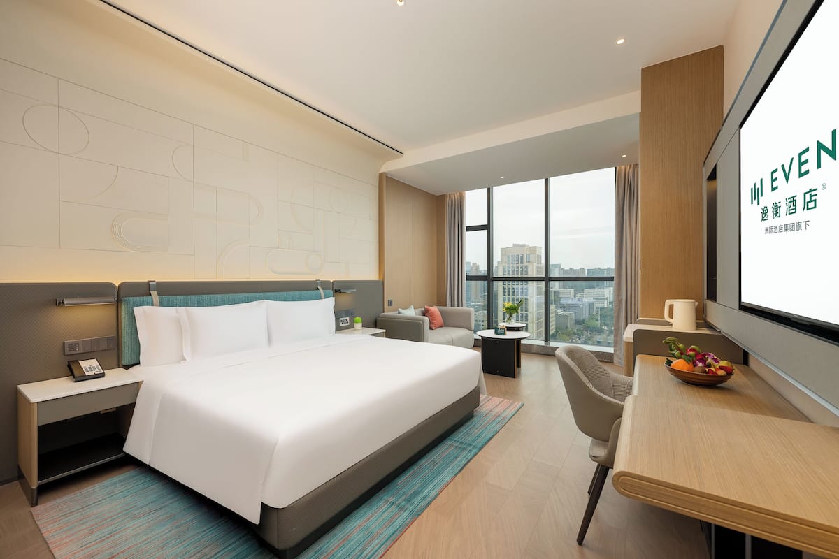 Una habitación de hotel moderna con una cama grande, un escritorio y vistas a la ciudad.