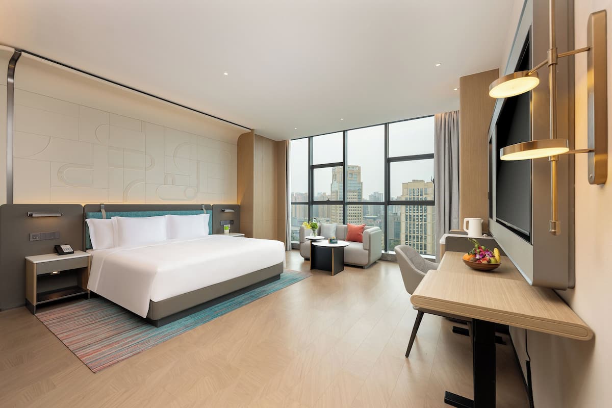 Una habitación de hotel moderna con una cama grande, un escritorio, un sofá y un televisor.
