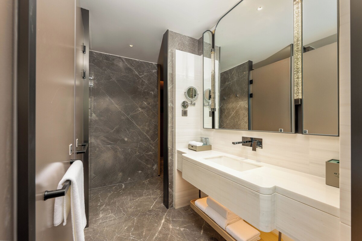 A modern bathroom with a large mirror, a sink, and a towel rack.