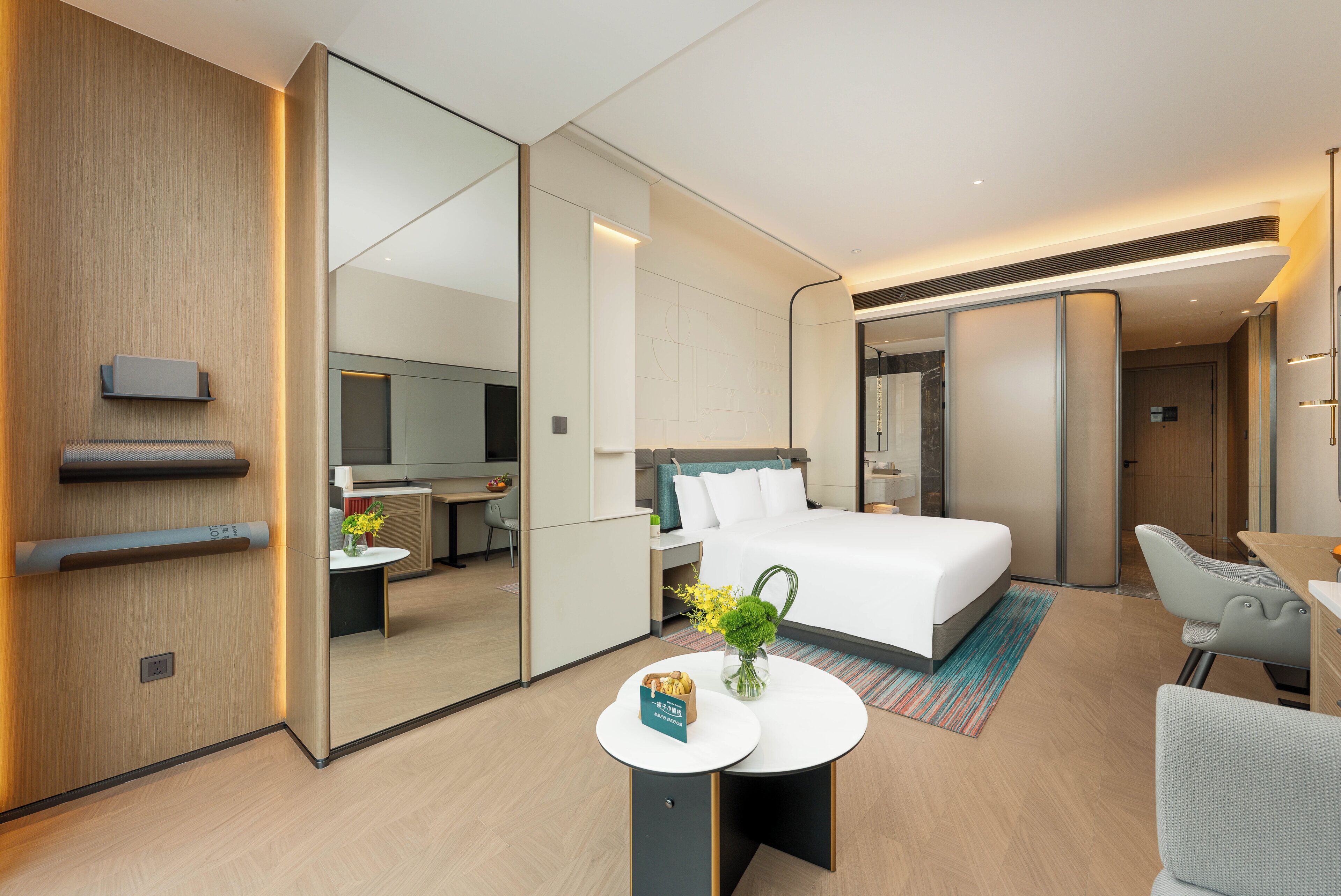 Una habitación de hotel moderna con una cama grande, un escritorio, una silla y una pequeña mesa con un florero.