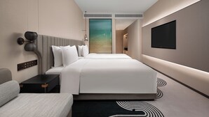 Una habitación de hotel moderna con una cama grande, un televisor de pantalla plana montado en la pared, una mesita de noche y una mesilla.
