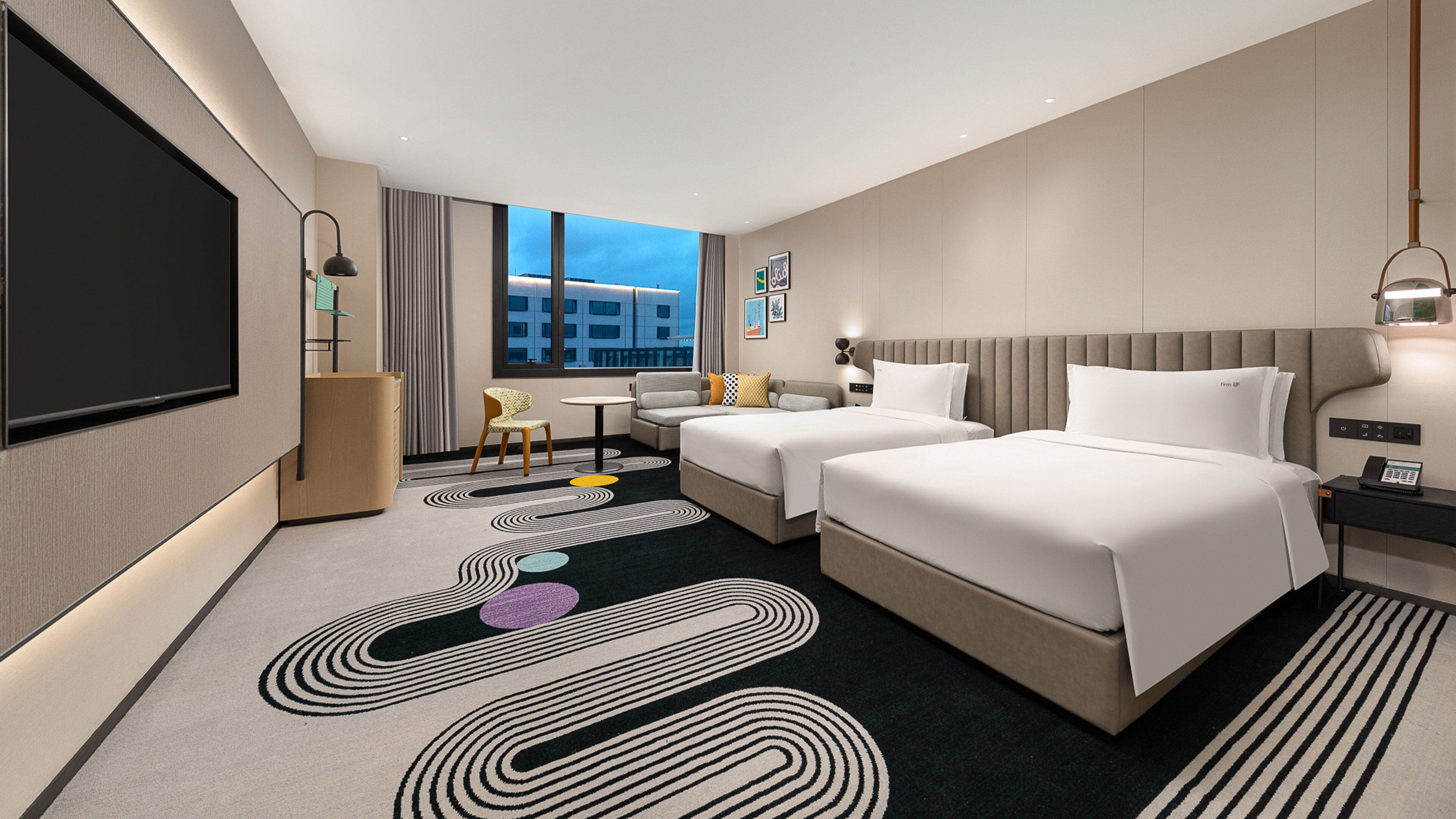 Habitación de hotel moderna con dos camas, televisión, escritorio y vista a la ciudad.