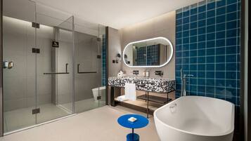 A modern bathroom with a glass shower enclosure, a freestanding bathtub, and a vanity with a mirror.