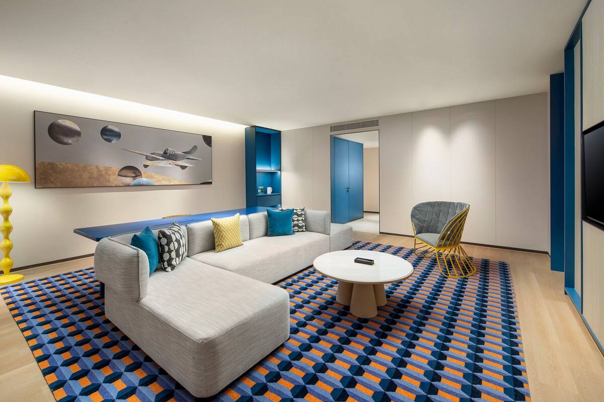 A modern living room with a sofa, coffee table, and a patterned rug.