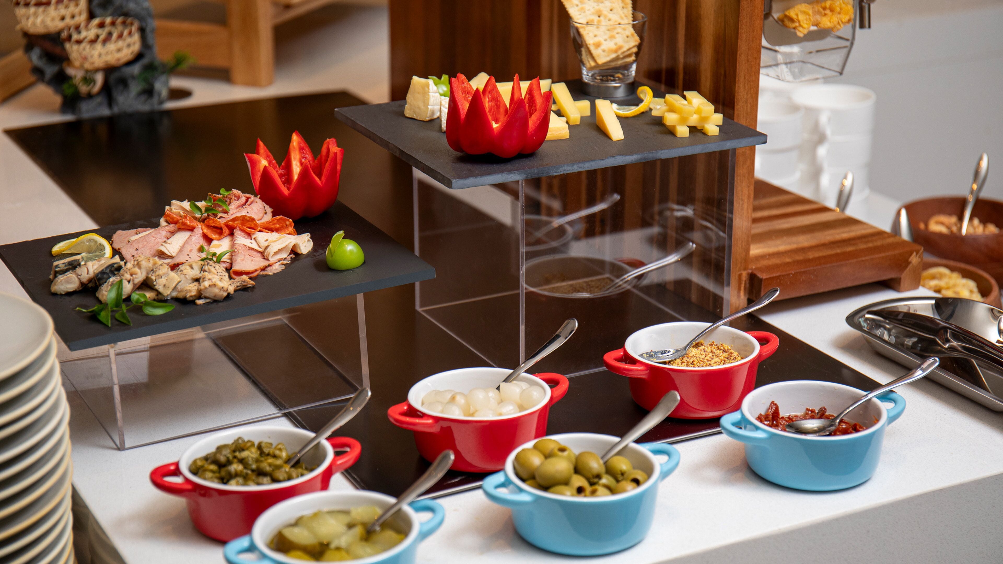 A buffet with various food items including cheese, olives, and a decorative flower centerpiece.