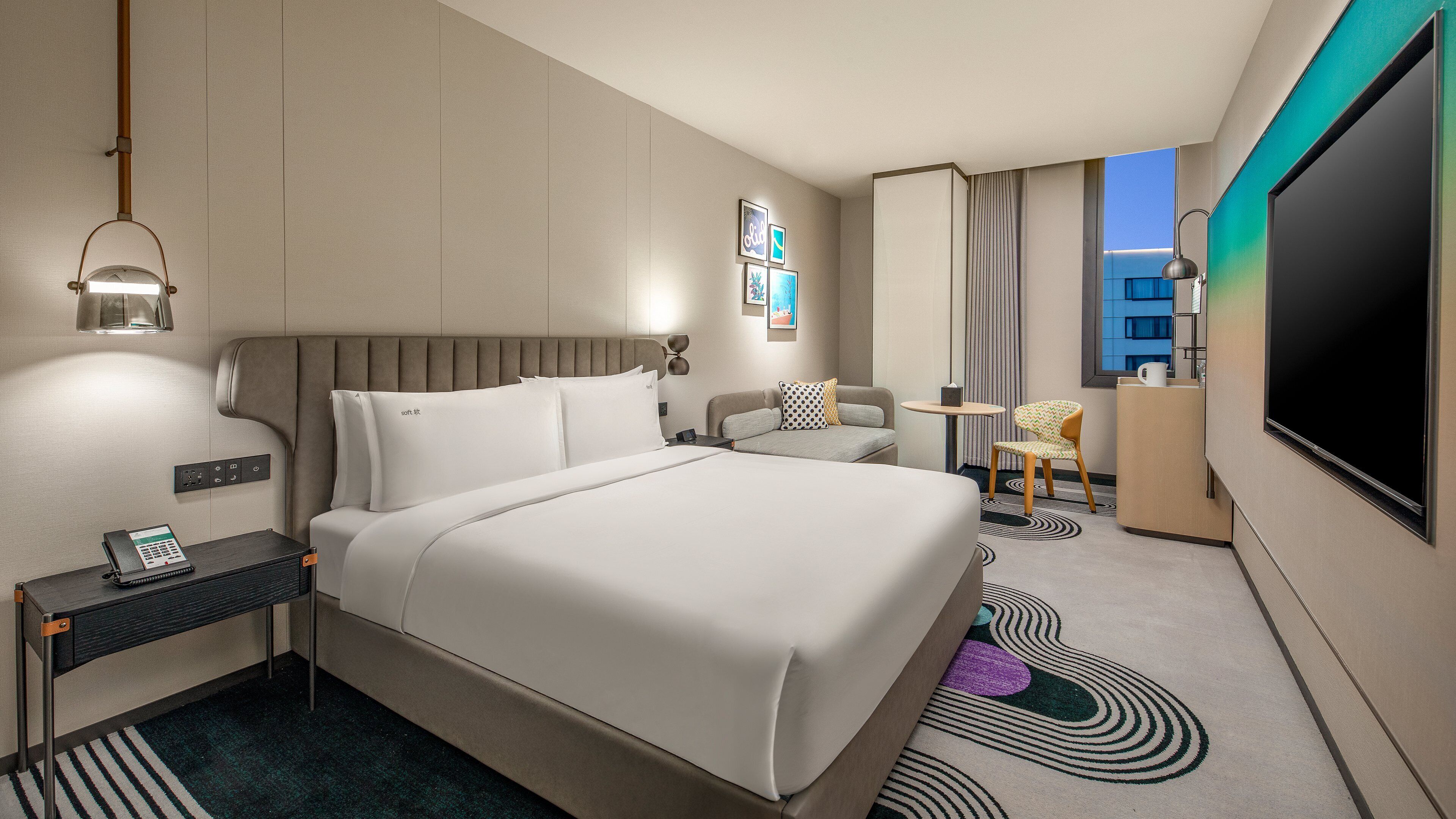 Une chambre d’hôtel équipée d’un lit, d’une table de chevet, d’une lampe, d’une chaise, d’un bureau et d’un téléviseur à écran plat.