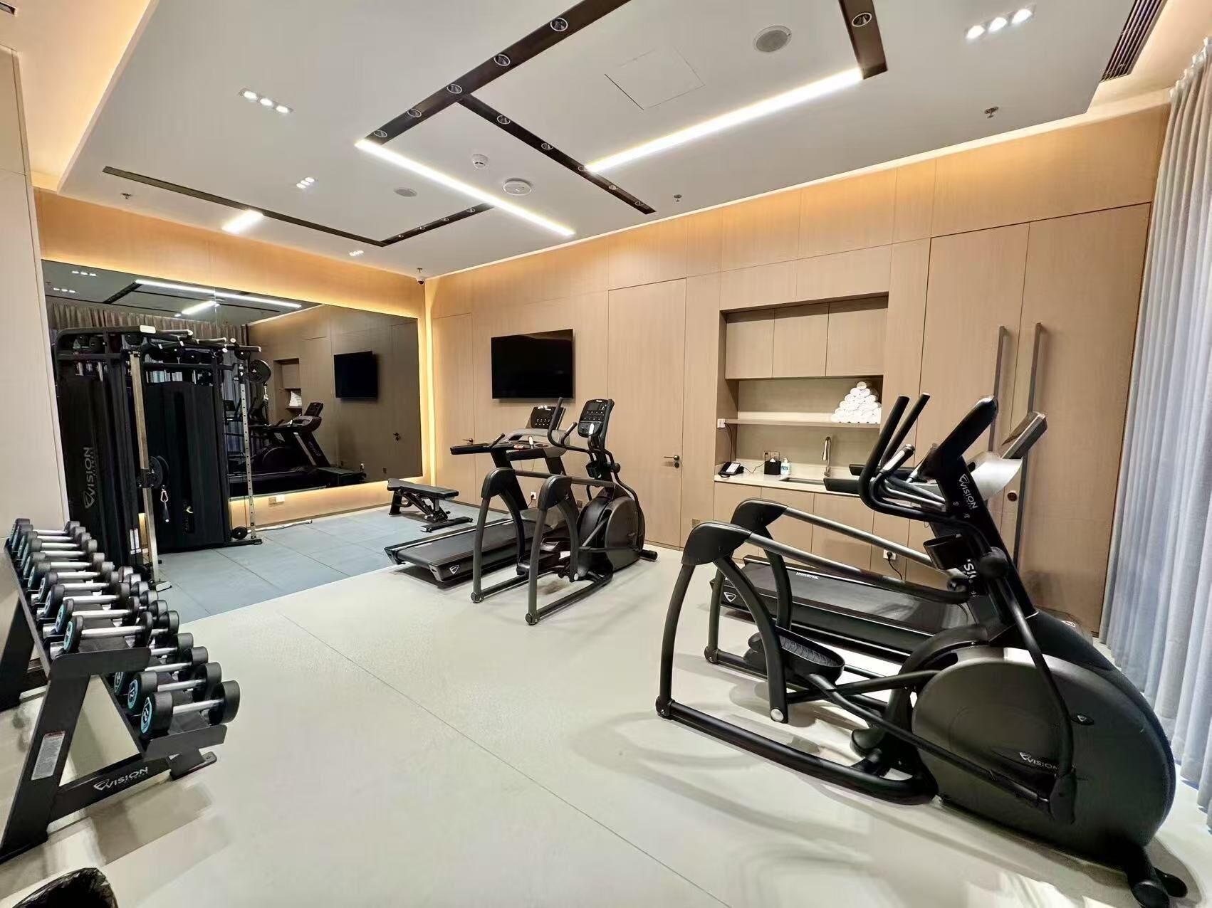 A modern gym with treadmills, elliptical machines, and weightlifting equipment.