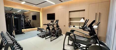 A modern gym with treadmills, elliptical machines, and weightlifting equipment.