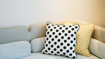 A sofa with three pillows: one with a polka dot pattern, one with a chevron pattern, and one plain.