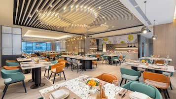 Un restaurant modern amb diverses sales de dinar, cadascuna amb taules i cadires.