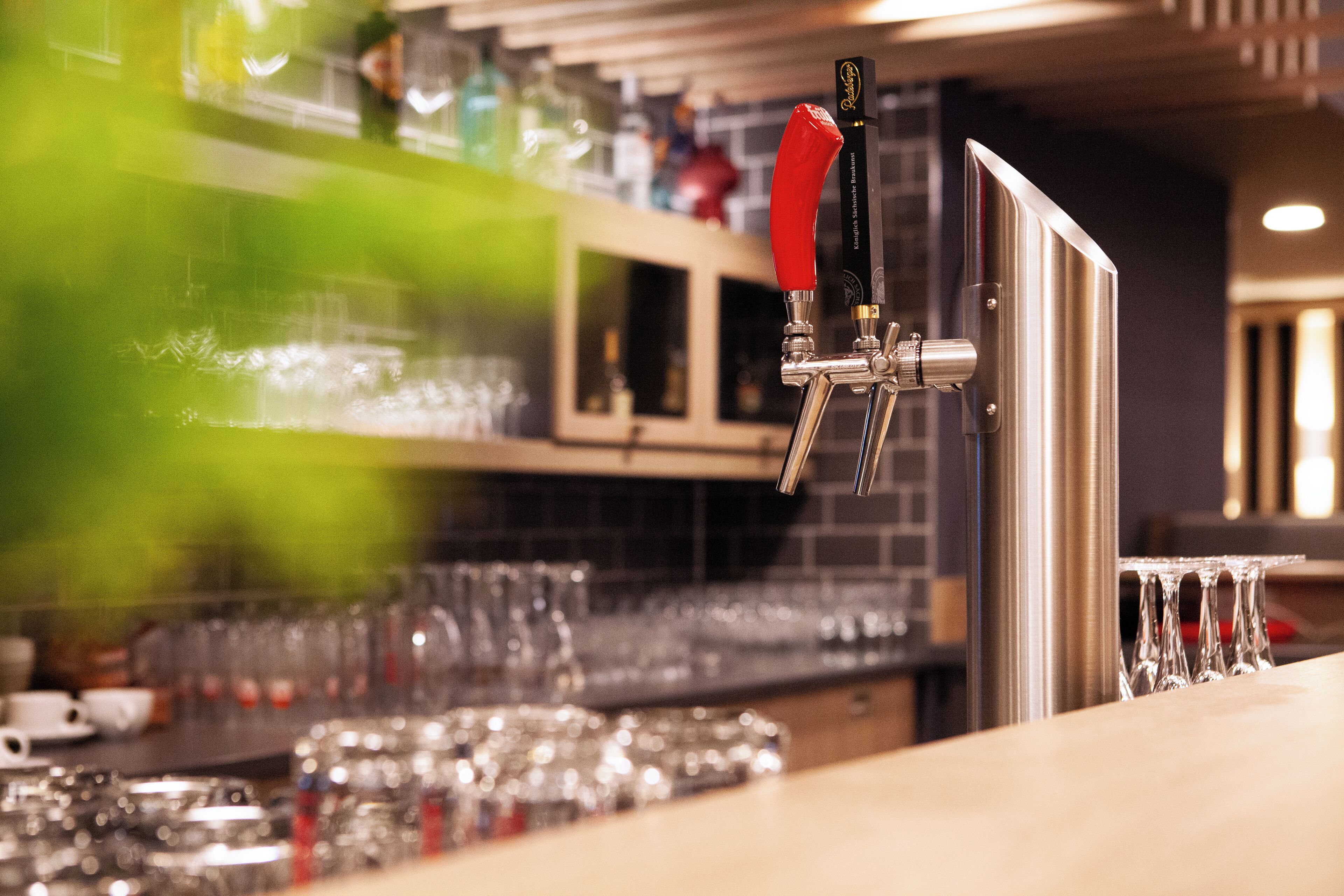 A bar area with a tap, glasses, and bottles.