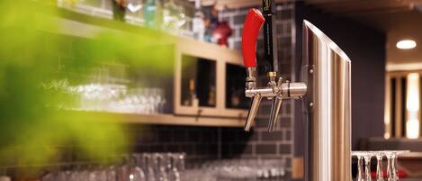 A bar area with a tap, glasses, and bottles.