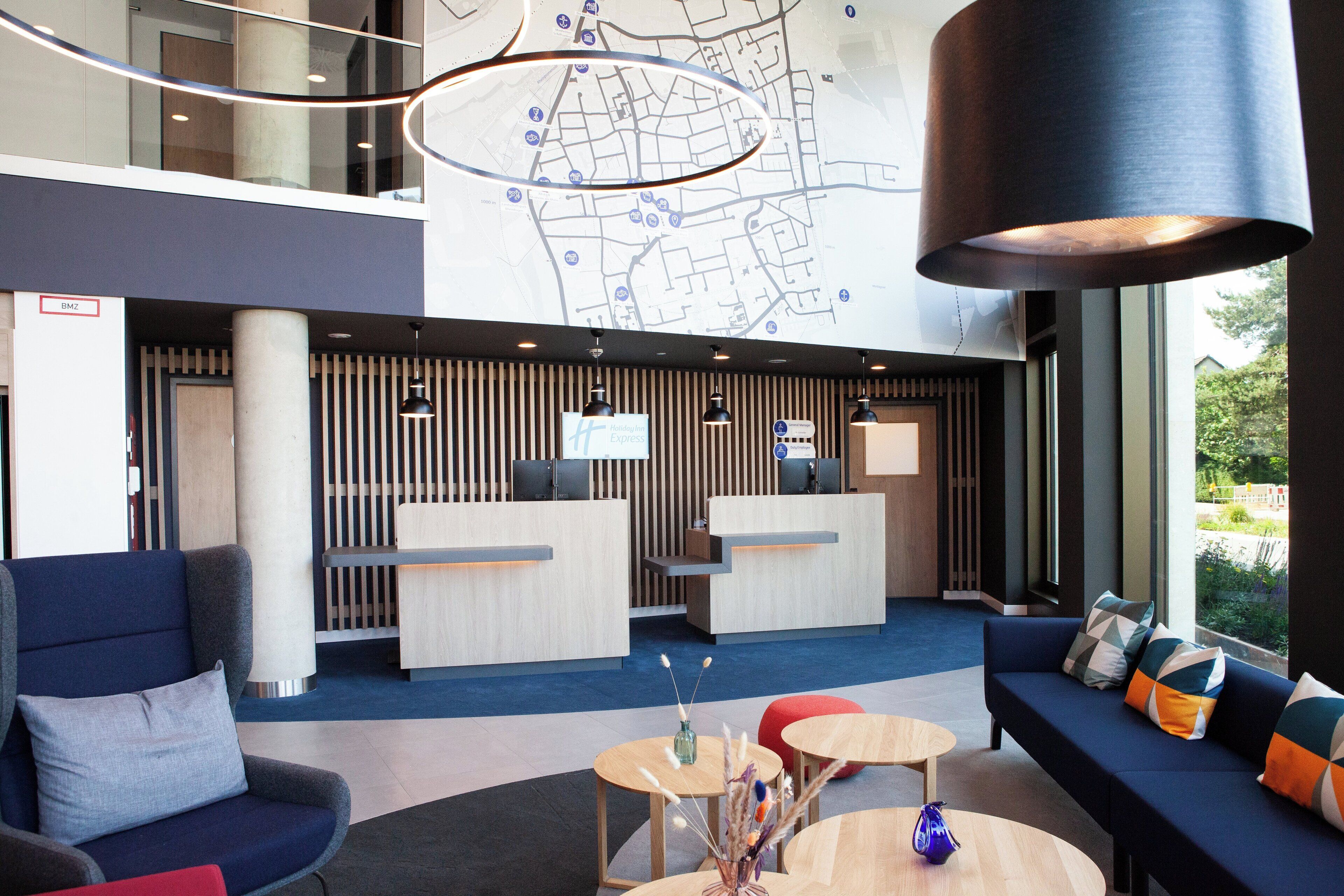 A hotel lobby with a reception desk, seating area, and a map on the wall.