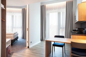 A modern hotel room with a bed, a dining table, and a kitchenette. - Holiday Inn Express & Suites Monheim Am Rhein by IHG (Monheim)