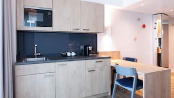 A modern kitchen with wooden cabinets, a built-in microwave, and a dining area with a table and chairs.