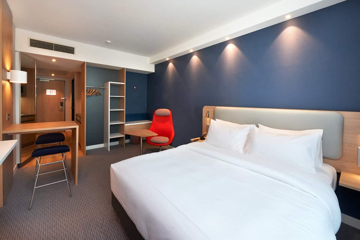 A hotel room with a bed, desk, chair, and wardrobe.