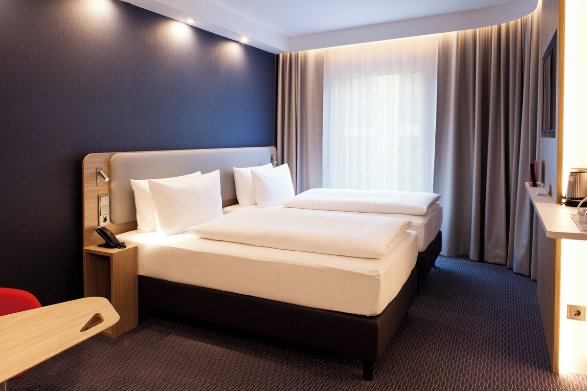 A hotel room with a large bed, bedside tables, a desk, and a chair.
