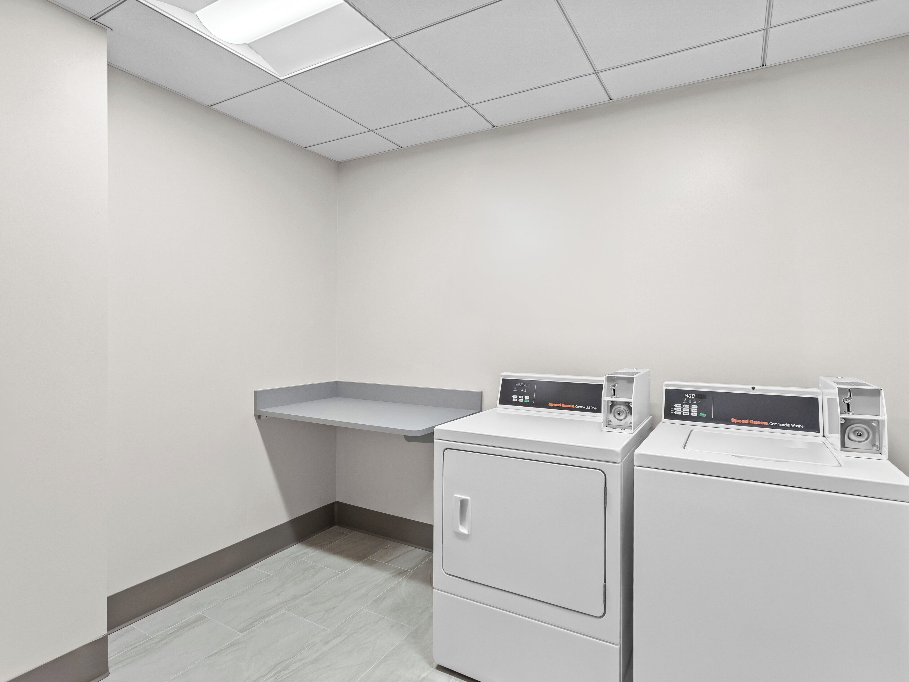 A laundry room with two front-loading washers and a single dryer.