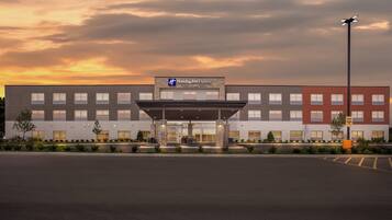 A Holiday Inn Express hotel with a modern facade, large windows, and a parking lot.