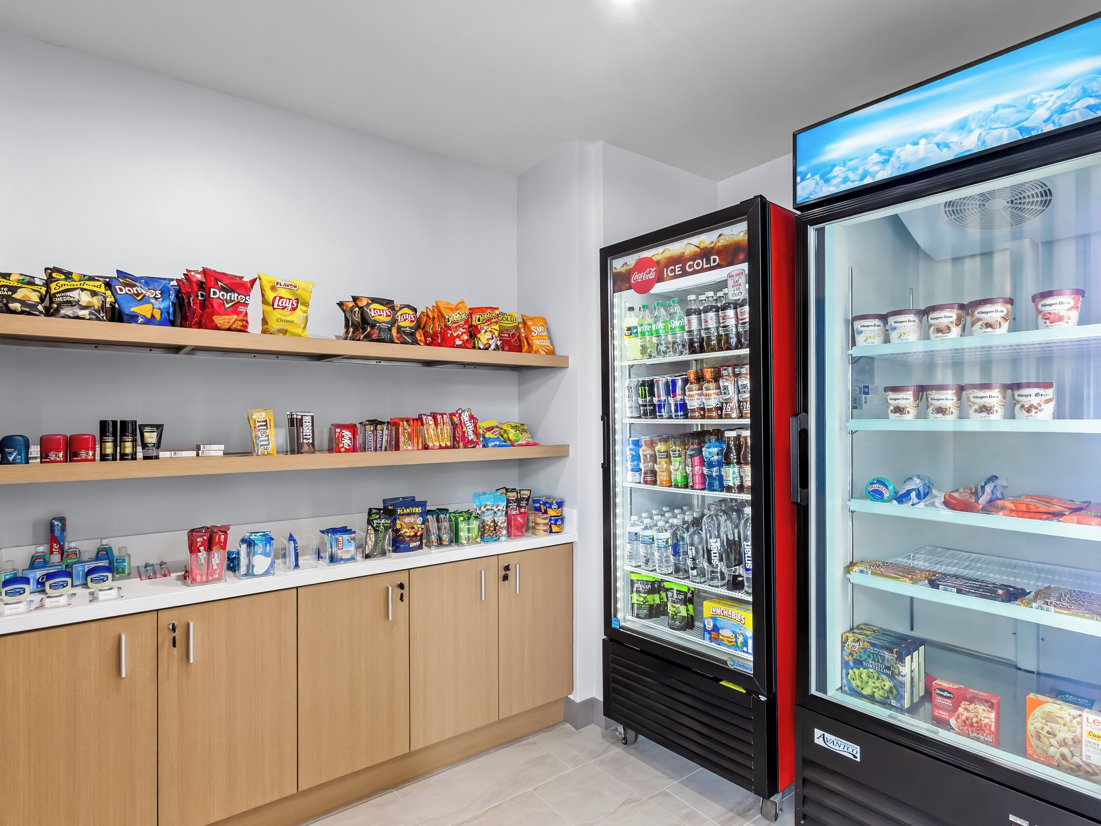 Un distributeur automatique rempli d’en-cas et de boissons, une étagère avec divers produits emballés et un réfrigérateur contenant des aliments.