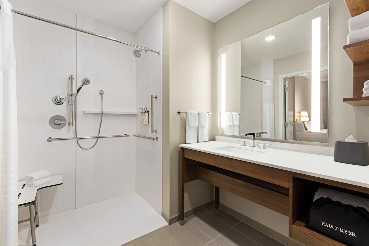 Une salle de bain moderne avec une douche à l’italienne, un meuble-lavabo avec un miroir et un porte-serviettes.