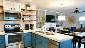 A modern kitchen with stainless steel appliances, blue cabinets, and a central island. - PRIVATE and serene riverfront retreat - LARGE spacious yard with a cozy home!  (Canyon Lake)