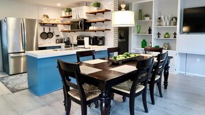 A modern kitchen with a central island, stainless steel appliances, and a dining area with wooden chairs. - PRIVATE and serene riverfront retreat - LARGE spacious yard with a cozy home!  (Canyon Lake)
