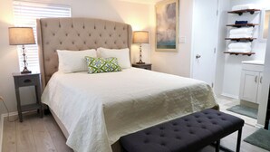 A neatly arranged bedroom with a large bed, bedside lamps, a bench, and a wardrobe. - PRIVATE and serene riverfront retreat - LARGE spacious yard with a cozy home!  (Canyon Lake)
