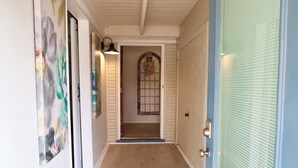 A hallway with a wooden floor, a door with a metal handle, and a wall with a floral painting. - PRIVATE and serene riverfront retreat - LARGE spacious yard with a cozy home!  (Canyon Lake)