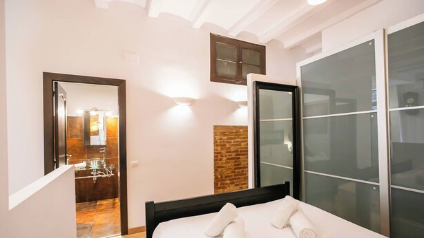 Una habitación de hotel con cama, baño con espejo y puerta corrediza de vidrio.