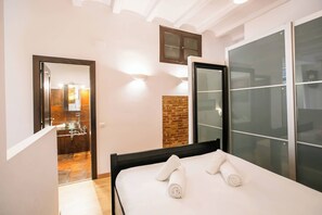 A hotel room with a bed, a bathroom with a mirror, and a sliding glass door.